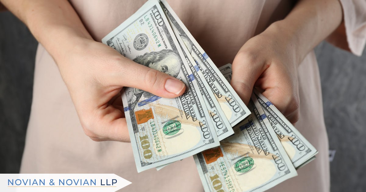 Hands counting one hundred dollar bills from a personal injury settlement