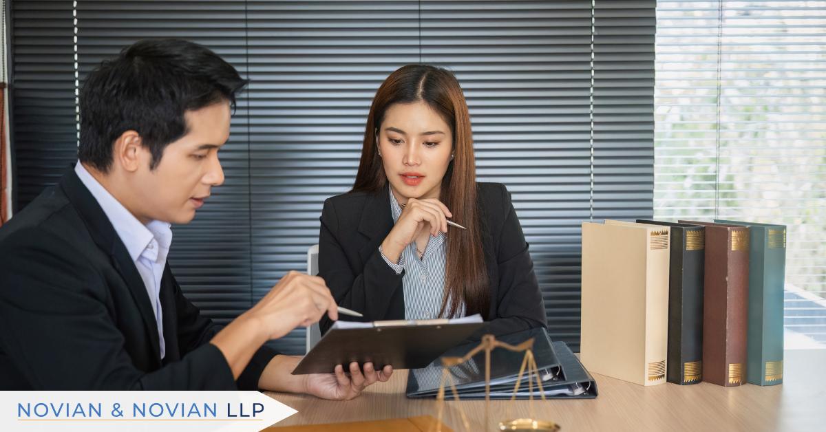 Two professionals review workplace documentation together beside binders and the scales of justice, illustrating how thorough records can change the course of an EEOC defense.
